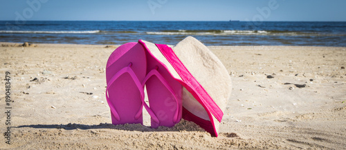 Straw hat and slippers on sand at beach. Accessories for relax in summer