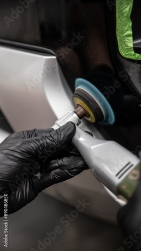Obraz na płótnie Hand wearing black glove polishing car body using electric buffer, focusing on meticulous auto detailing for perfect finish. Professional car maintenance emphasizing high-quality, shiny surface. w salonie