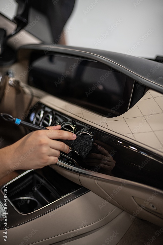Detailing interior car dashboard using brush, ensuring thorough cleaning and high-quality finish. Focus on precision and cleanliness in professional auto detailing