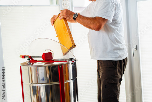 Beekeeper Putting Beehive Frame into a Centrifugal Extraxtor for Bee Honey Harvest photo