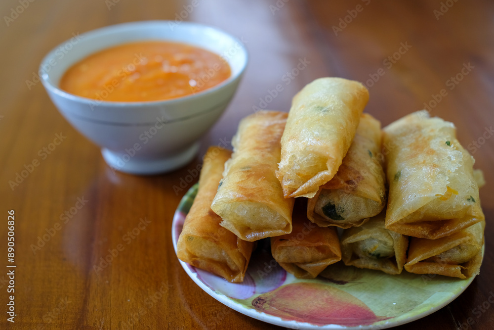 Fried spring rolls on white plate, served with chili sauce sambal on top the wood table, traditional snack, Traditional spring rolls, copy space . Fried spring rolls on white plate, served with chili sauce sambal on top the wood table, traditional snack, Traditional spring rolls, copy space .