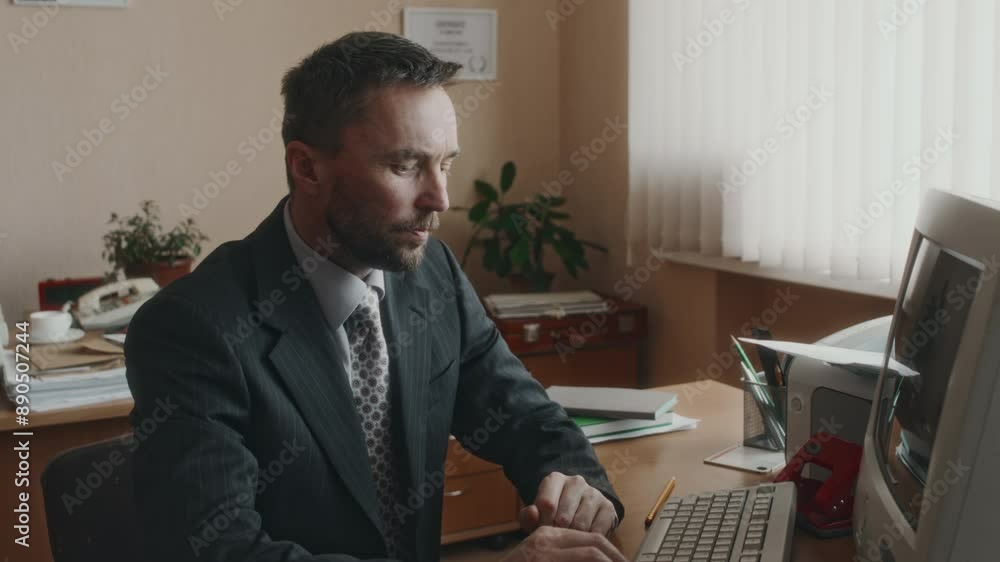 Side medium shot of experienced bearded Caucasian office worker giving advice about documents to diverse colleague and continuing working on outdated computer in 90s retro office Side medium shot of experienced bearded Caucasian office worker giving advice about documents to diverse colleague and continuing working on outdated computer in 90s retro office