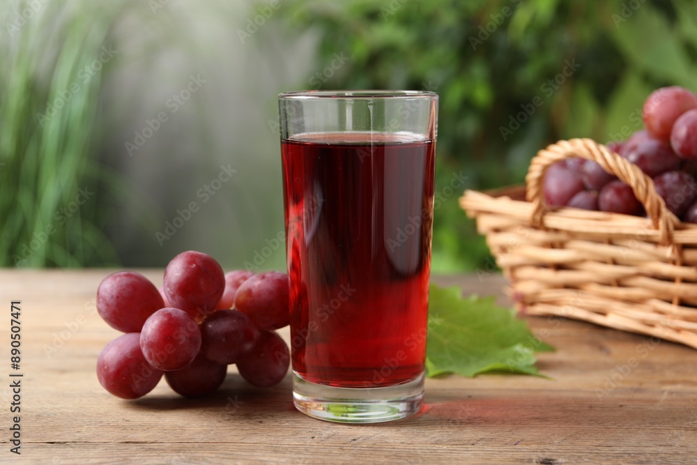 Tasty juice in glass, fresh grapes and leaf on wooden table Tasty juice in glass, fresh grapes and leaf on wooden table