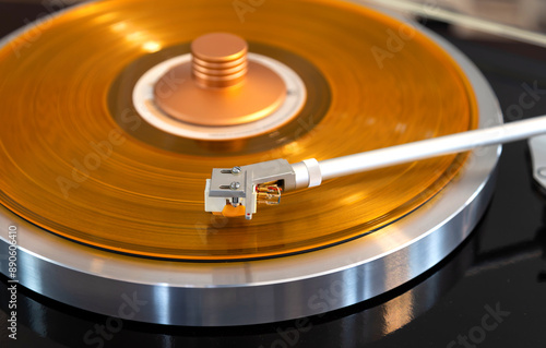 Vintage Stereo Turntable Record Player Tonearm Above Yellow Colored Vinyl photo