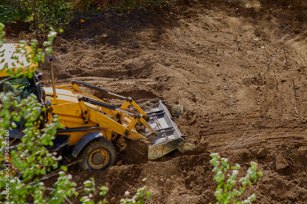 Earthworks at the construction site: bulldozer leveling the ground against greenery. Earthworks at the construction site: bulldozer leveling the ground against greenery.