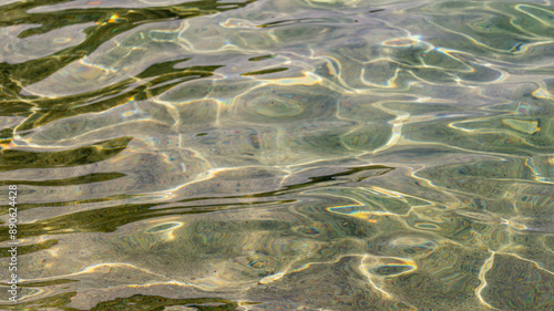 Clear shallow sea water over sand and rocks, sunlit liquid texture