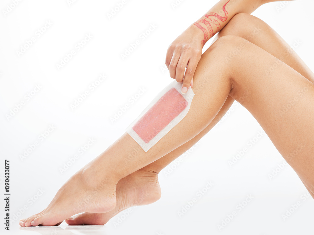 Fototapeta premium Woman, leg and wax strip in studio, hair removal and healthy skincare on white background. Body wellness, hand and pull cosmetic product for grooming routine, smooth skin and pedicure feet for beauty