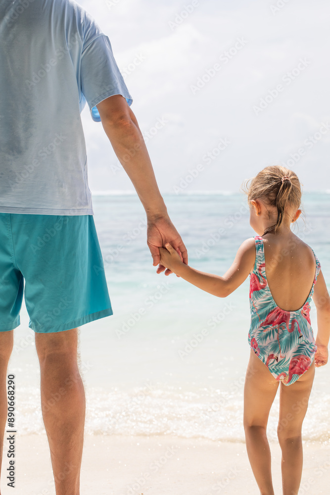 Little girl holding dad's hand, ocean in the background, child protection, child care, family, father and daughter. Father's Day, Family Day. Little girl holding dad's hand, ocean in the background, child protection, child care, family, father and daughter. Father's Day, Family Day.
