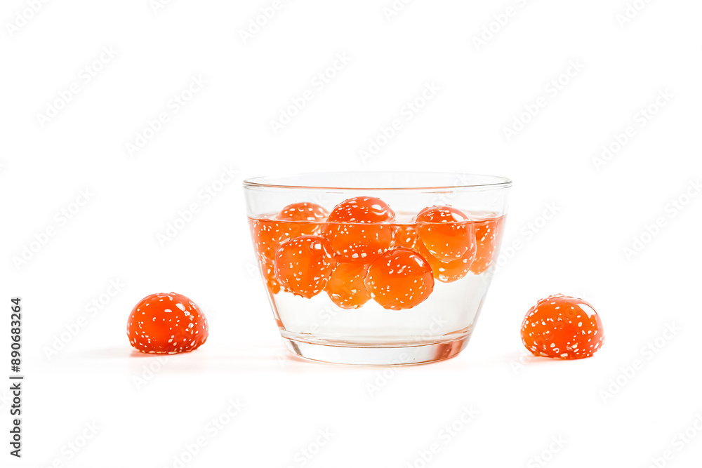 Orange jelly balls in a glass of water on a white background Orange jelly balls in a glass of water on a white background