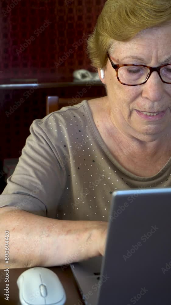 Senior woman studying with a laptop and a book at home. Real time video. Senior woman studying with a laptop and a book at home. Real time video.