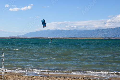 Kitesurfer is riding a wave on a sunny day with blue sky