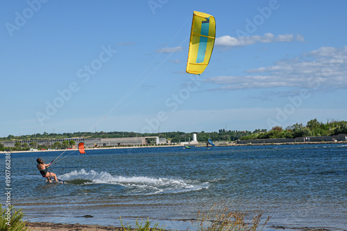 Kitesurfer is riding a wave on a sunny day with blue sky