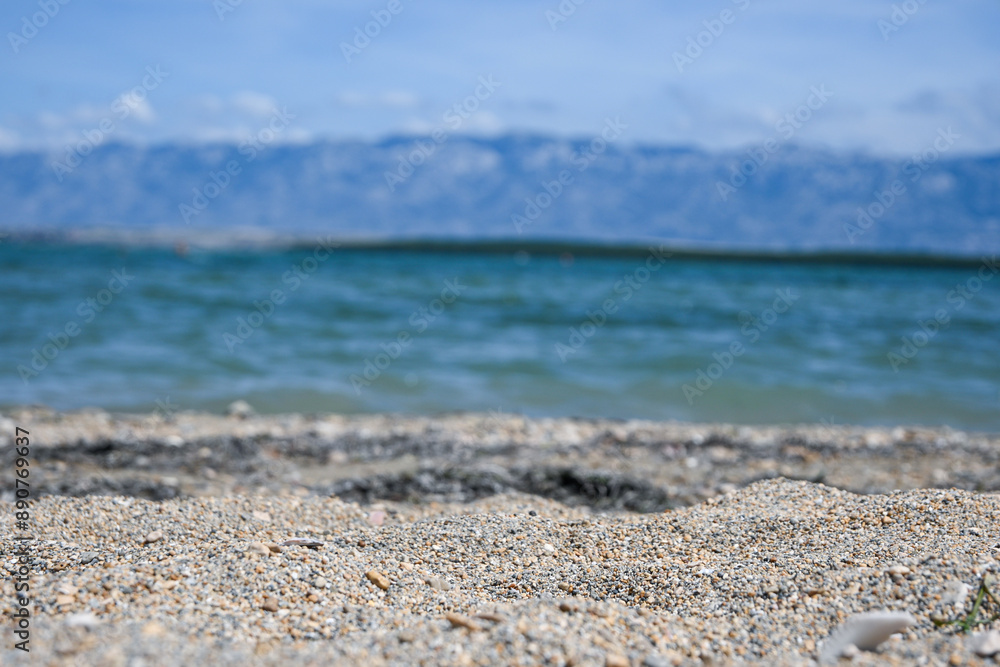 Fine gravel beach with blurred ocean and mountains providing a serene background Fine gravel beach with blurred ocean and mountains providing a serene background