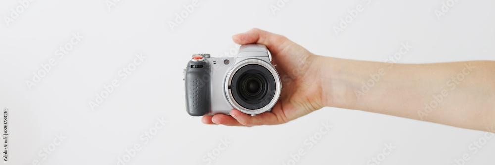 A person is holding a camera with a lens. The camera is silver and black A person is holding a camera with a lens. The camera is silver and black