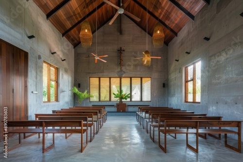 A church with wooden pews and a cross hanging from the ceiling. The pews are empty and the room is dimly lit