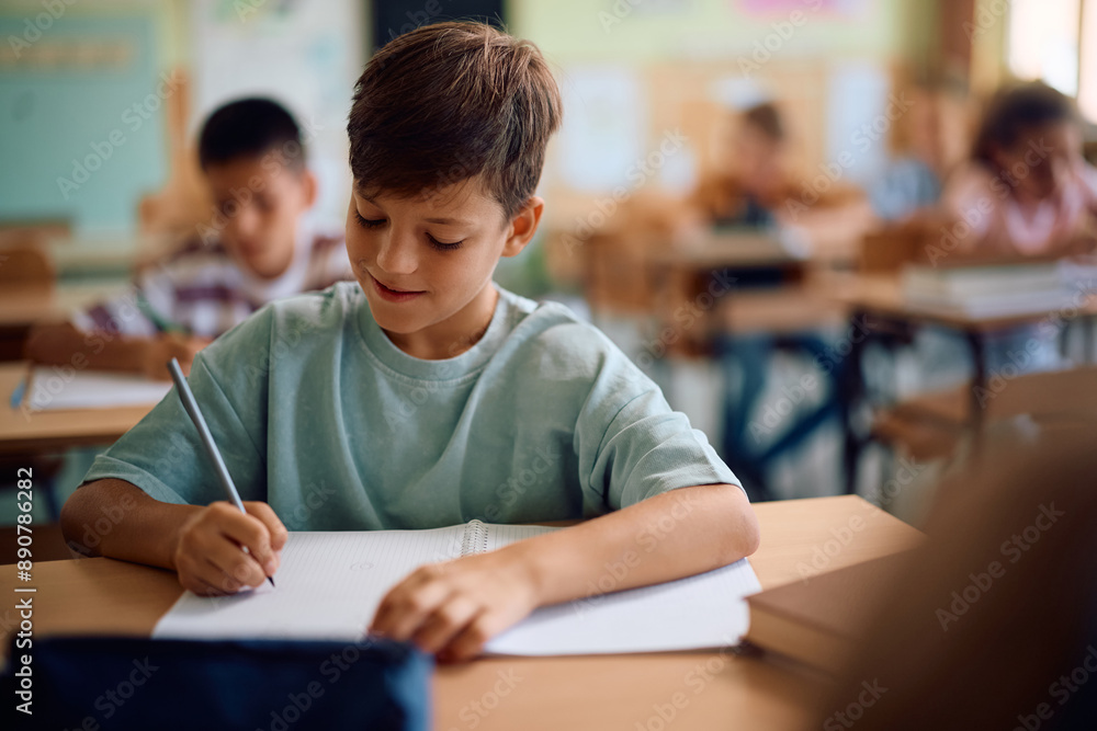 Smiling schoolboy writing test during class in classroom. Smiling schoolboy writing test during class in classroom.