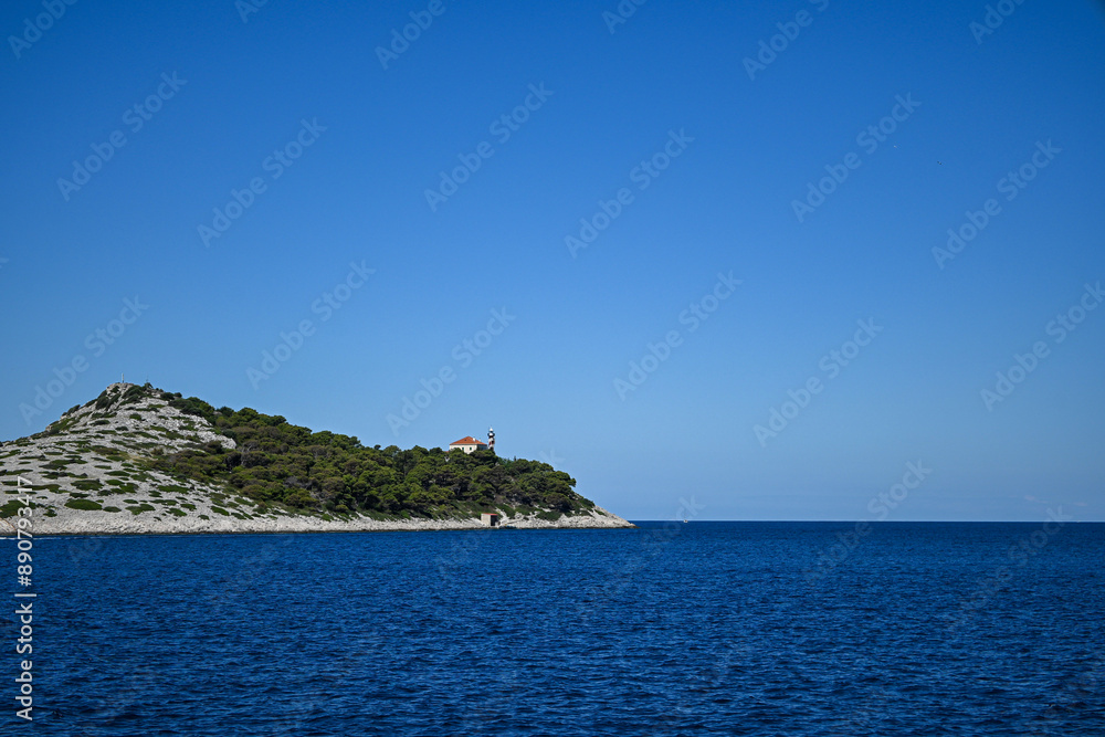 Small rocky island emerging from the deep blue sea on sunny summer day Small rocky island emerging from the deep blue sea on sunny summer day