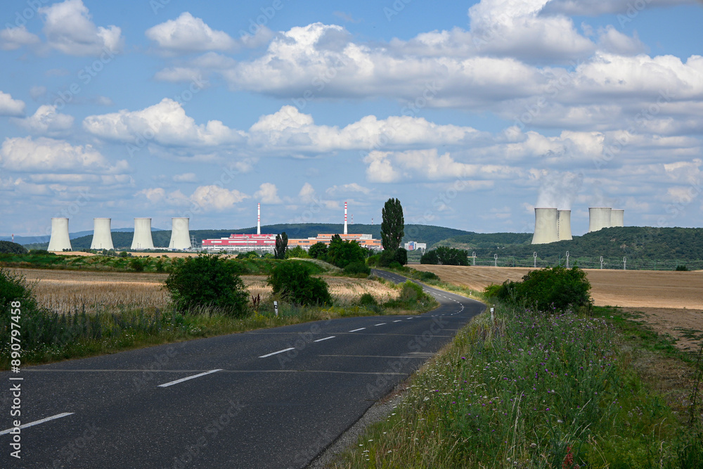 Empty country road is leading to a nuclear power plant with big cooling towers on a sunny day Empty country road is leading to a nuclear power plant with big cooling towers on a sunny day