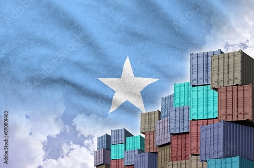 Somalia flag and big stack of shipping cargo containers in docks with sky background close up photo