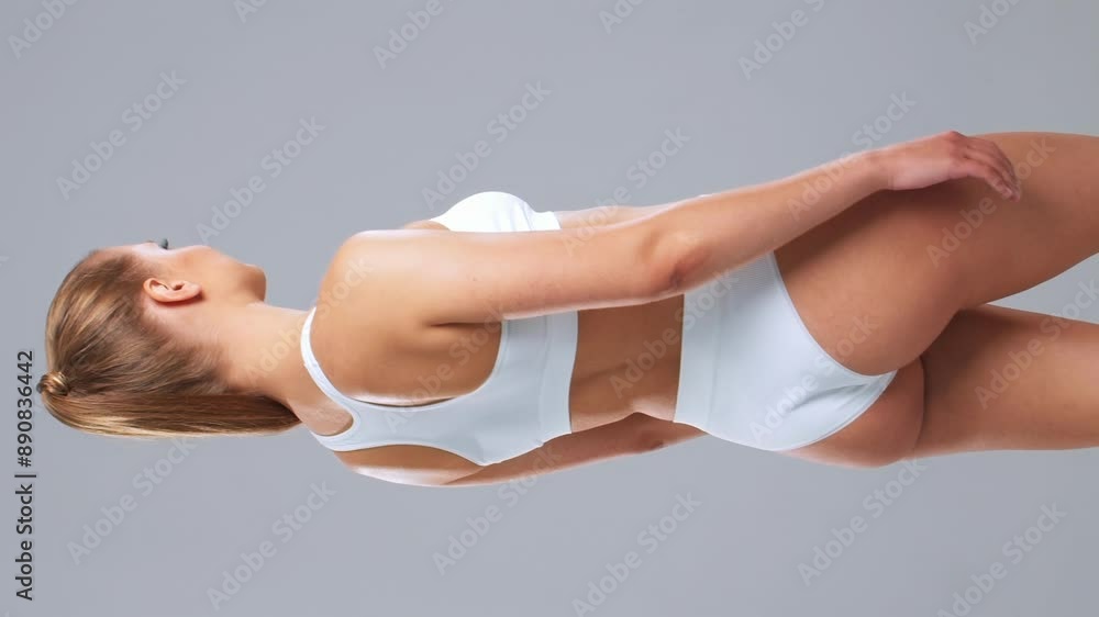 Young, fit and beautiful woman in white swimsuit posing over grey background. Vertical video. Healthcare, diet, sport and fitness. Young, fit and beautiful woman in white swimsuit posing over grey background. Vertical video. Healthcare, diet, sport and fitness.