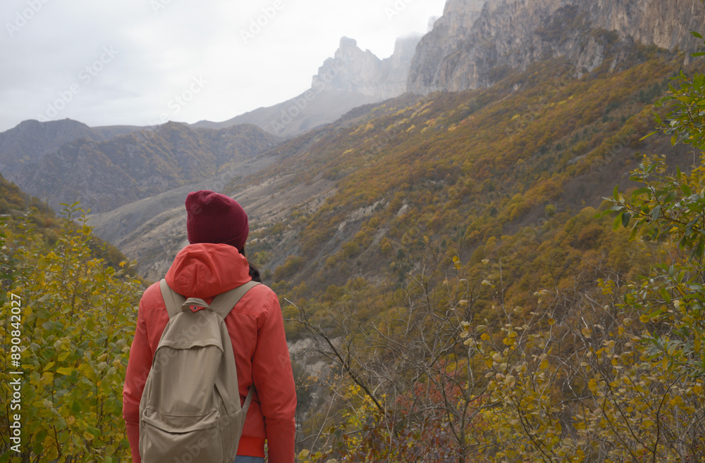 Brunette woman with a backpack on her back outdoors exploring the Caucasus Mountains in Russia, traveling, lifestyle, hiking, active autumn holidays, hiking