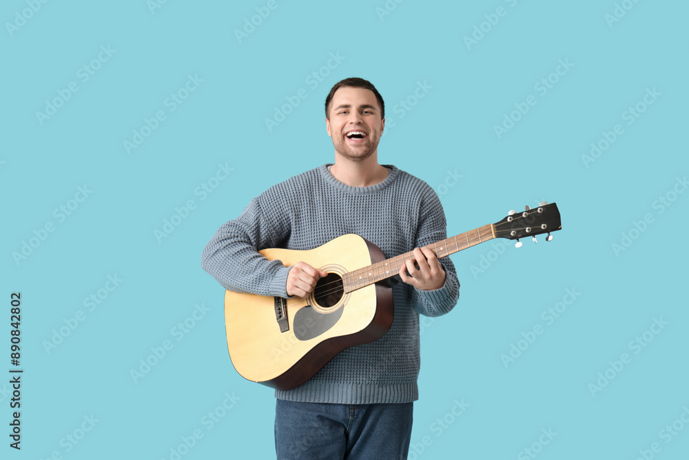 Handsome man playing guitar on blue background Handsome man playing guitar on blue background