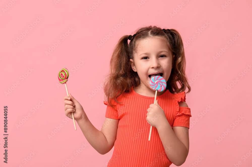 Cute little girl licking lollipop on pink background Cute little girl licking lollipop on pink background