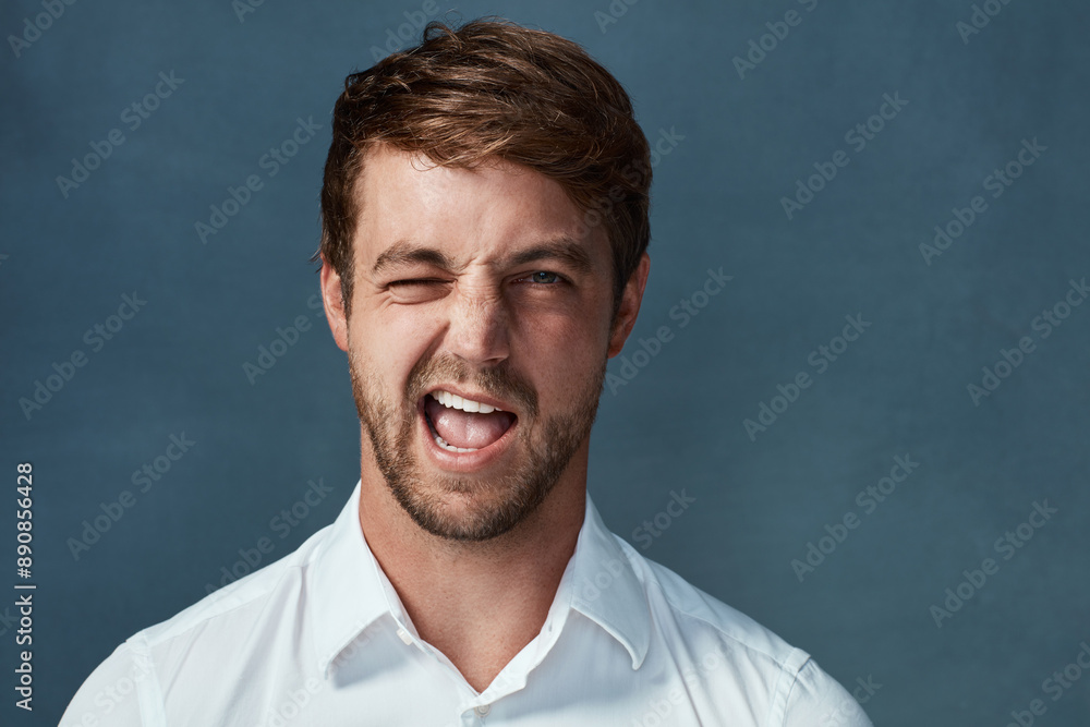 Wink, portrait and man in studio, happy and comic with confidence of publicist, excited and goofy. Blue background, funny face and person in public relations with comedy, joy and silly in mockup Wink, portrait and man in studio, happy and comic with confidence of publicist, excited and goofy. Blue background, funny face and person in public relations with comedy, joy and silly in mockup