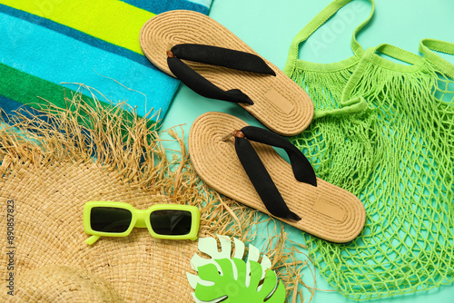 Fotografía Flip flops with string bag, towel, sunglasses and straw hat on turquoise backgro