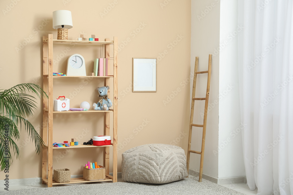 Rack with children toys, pouf and stepladder near beige wall Rack with children toys, pouf and stepladder near beige wall