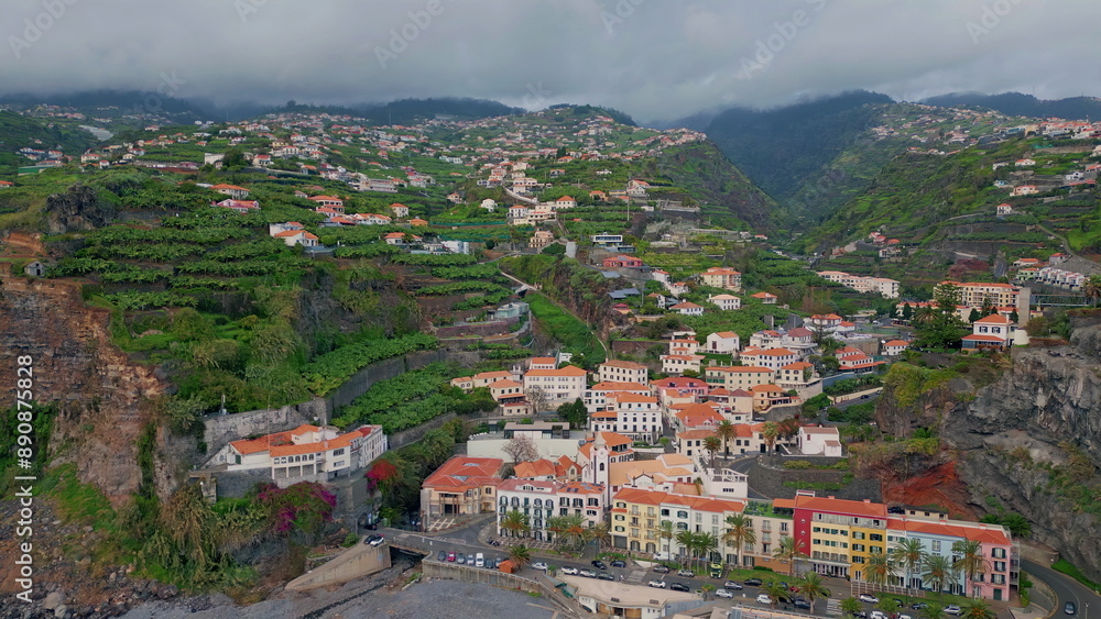 Fototapeta premium Aerial beautiful coastal settlement with terraced hills and green fields. 