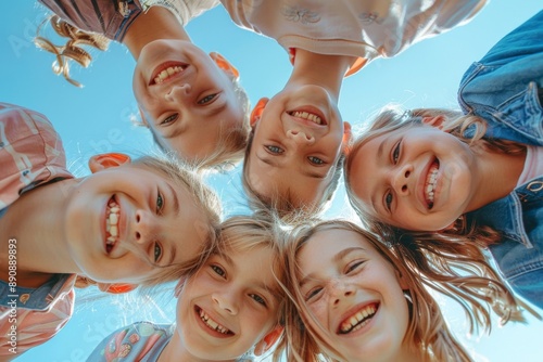 A group of happy and lovely children playing together, huddling and smiling down at the camera from a low angle, showcasing their friendship and joyful interaction. © 为轩 张