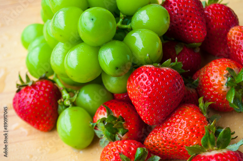 Mixture of strawberries and shining muscat on wooden table background. Suitable for fruits promotion