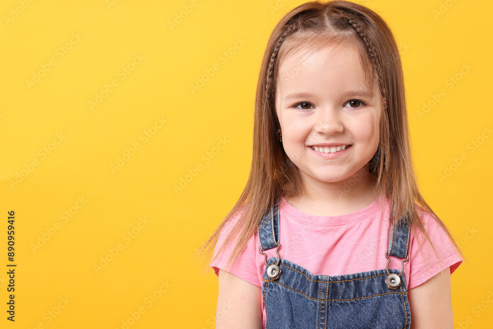Portrait of happy little girl on orange background, space for text