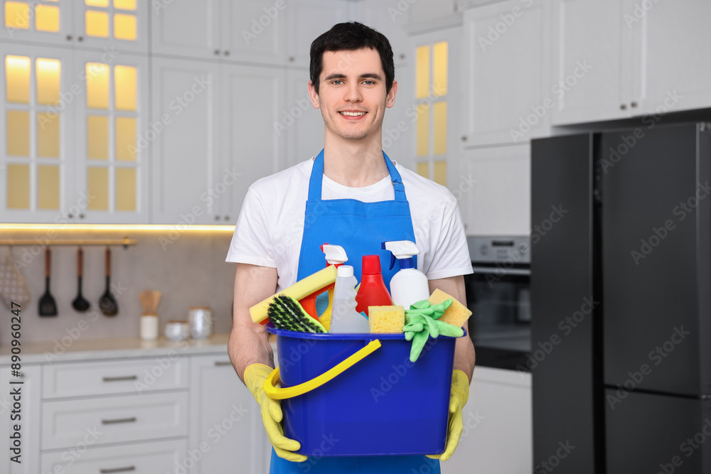 Cleaning service worker holding bucket with supplies in kitchen Cleaning service worker holding bucket with supplies in kitchen