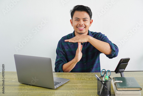 Cheerful young asian man sit work at wooden desk with pc laptop. Achievement business career lifestyle concept. Hold hands perpendicularly