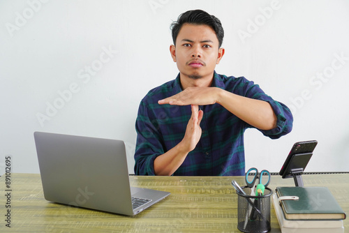 young asian man sit work at wooden desk with pc laptop. Achievement business career lifestyle concept. doing time out gesture with hands, frustrated and serious face