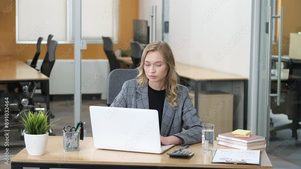A businesswoman wearing a gray plaid blazer over a black top, embodying professional attire. Professional woman busy working using her laptop and thinking ideas while touching her chin. A businesswoman wearing a gray plaid blazer over a black top, embodying professional attire. Professional woman busy working using her laptop and thinking ideas while touching her chin.