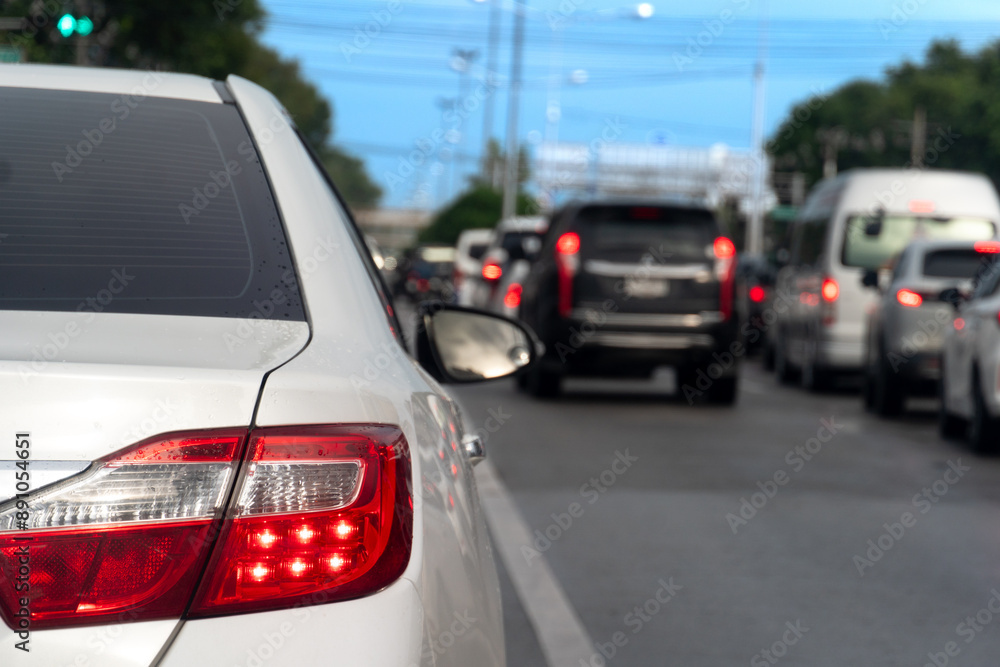 Fototapeta premium Luxury of white car stop on the asphalt road. Traveling in the provinces during the bright period. Open light brake. Many cars rushed forward in a long queue.