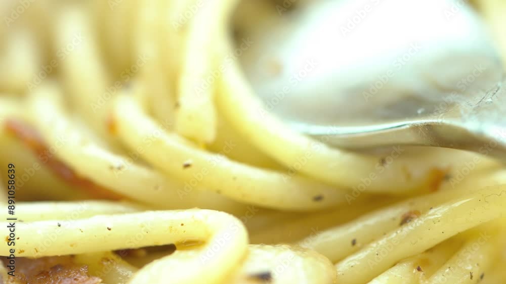 A spoon is in a pan of pasta with cheese. The pasta is covered in cheese and he is cooked