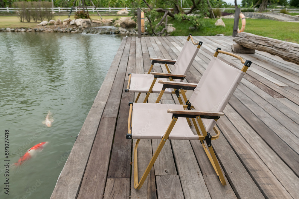 Picnic chairs on wood pergola by carp fish pond in spring garden Picnic chairs on wood pergola by carp fish pond in spring garden