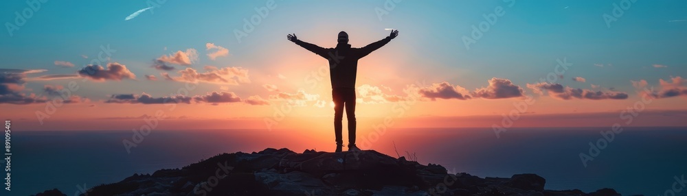Fototapeta premium Person standing with arms raised on mountain top during sunset, representing freedom, achievement, and connection with nature.