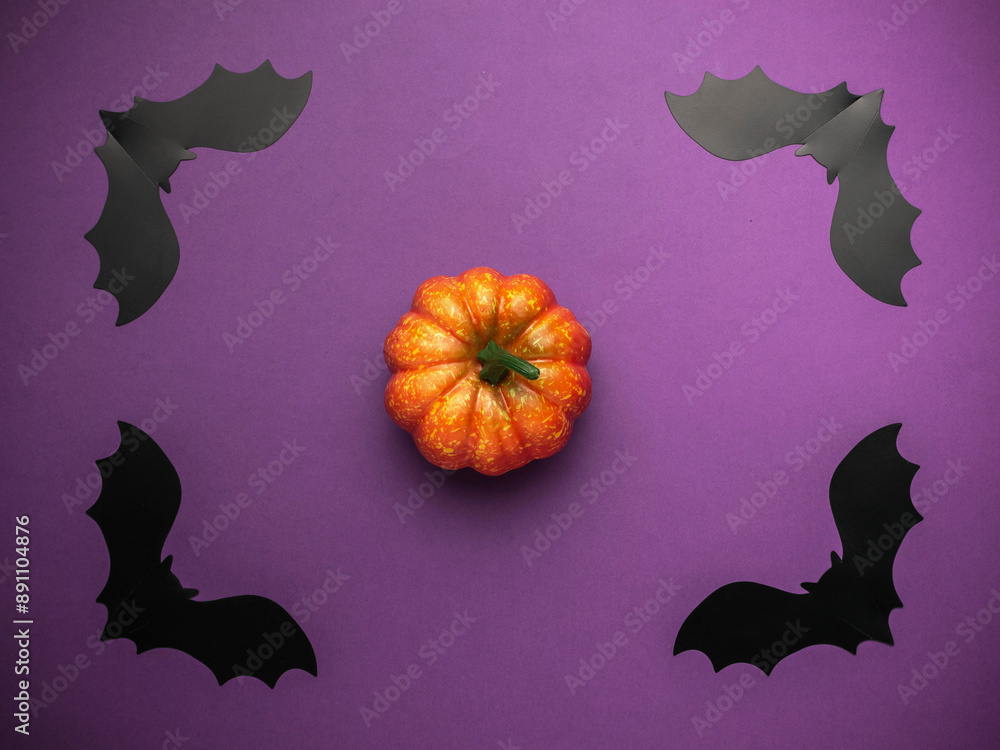Fototapeta premium Halloween Pumpkin Decoration with Black Paper Bats on Purple Background