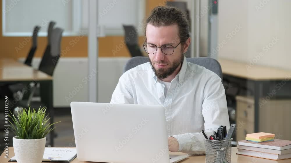 Professional office person with eyeglasses working on his laptop. A man having a headache and massaging his head with his hands. Professional office person with eyeglasses working on his laptop. A man having a headache and massaging his head with his hands.