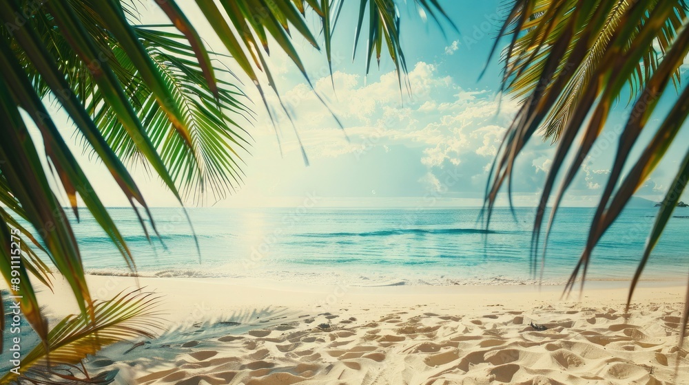 Fototapeta premium A serene tropical beach with white sand stretching into the distance, framed by palm tree leaves and bathed in warm sunlight.