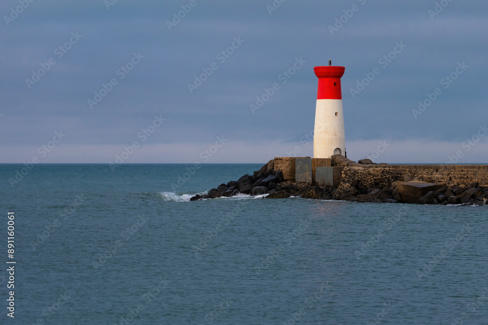 A lighthouse is on a rocky shoreline A lighthouse is on a rocky shoreline