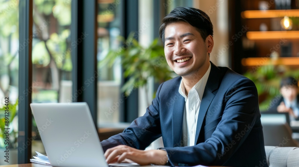 Happy businessman working on laptop in cafe. Portrait of a smiling businessman working on a laptop in a cafe. He is dressed in a suit and appears to be focused on his work. Happy businessman working on laptop in cafe. Portrait of a smiling businessman working on a laptop in a cafe. He is dressed in a suit and appears to be focused on his work.