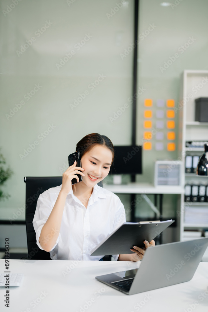 Asian businesswoman working with working notepad, tablet and laptop documents talking on the smartphone, tablet and laptop video call tax Asian businesswoman working with working notepad, tablet and laptop documents talking on the smartphone, tablet and laptop video call tax