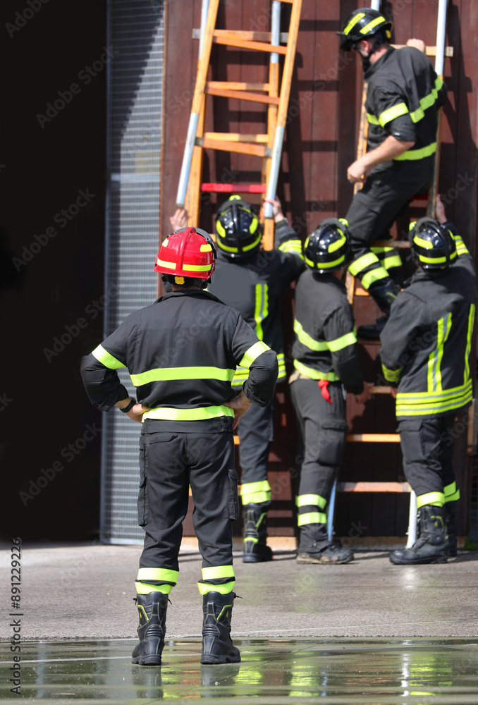 Obraz premium Fireman Fire chief coordinates firefighters assembling stepladder to climb building