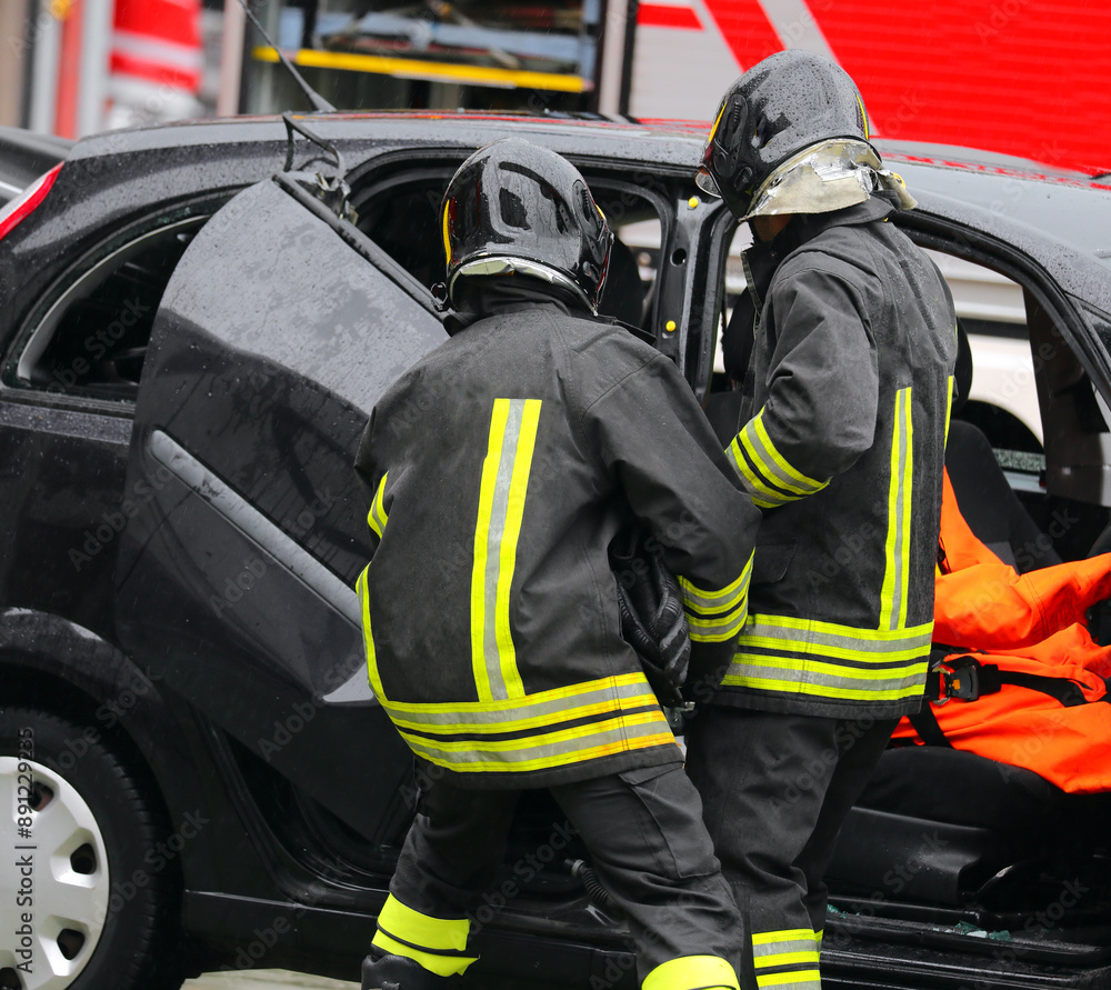 Firefighters open the doors of the crashed car to save the injured person Firefighters open the doors of the crashed car to save the injured person